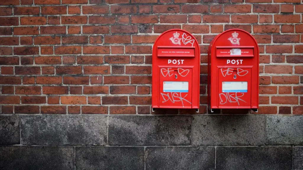 Deux boîtes aux lettres rouges fixées sur un mur en briques traditionnel.