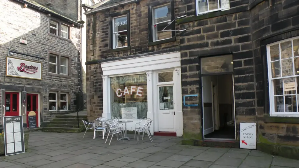 Façade d'un café avec tables en extérieur sur une rue pavée européenne.