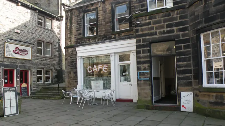 Façade d'un café avec tables en extérieur sur une rue pavée européenne.