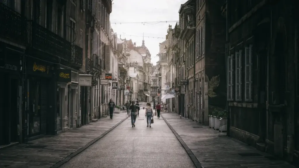 Des piétons marchent dans une rue étroite de style européen avec architecture ancienne.