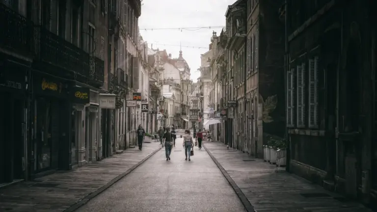 Des piétons marchent dans une rue étroite de style européen avec architecture ancienne.