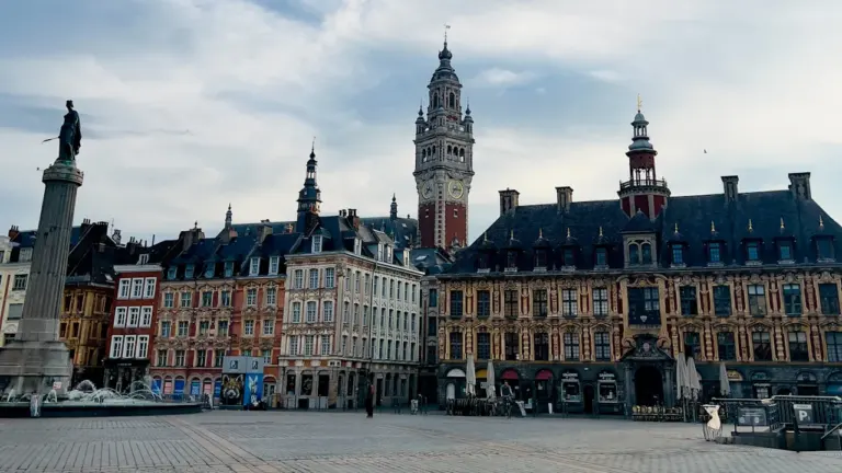 Grande place historique avec bâtiments anciens et monument central emblématique à Lille.