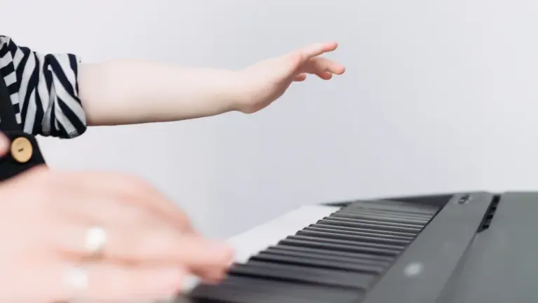 Mains d'un enfant apprenant à jouer du piano sur un clavier.