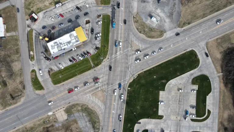 Vue aérienne d'un carrefour urbain aménagé avec des voies de circulation et stationnement.
