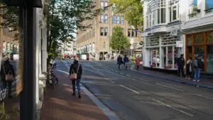 Rue commerçante animée et ensoleillée avec des piétons se promenant à Amsterdam.