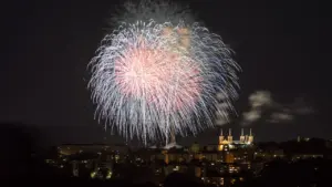 Grand feu d'artifice illuminant le ciel nocturne au-dessus d'une ville française.