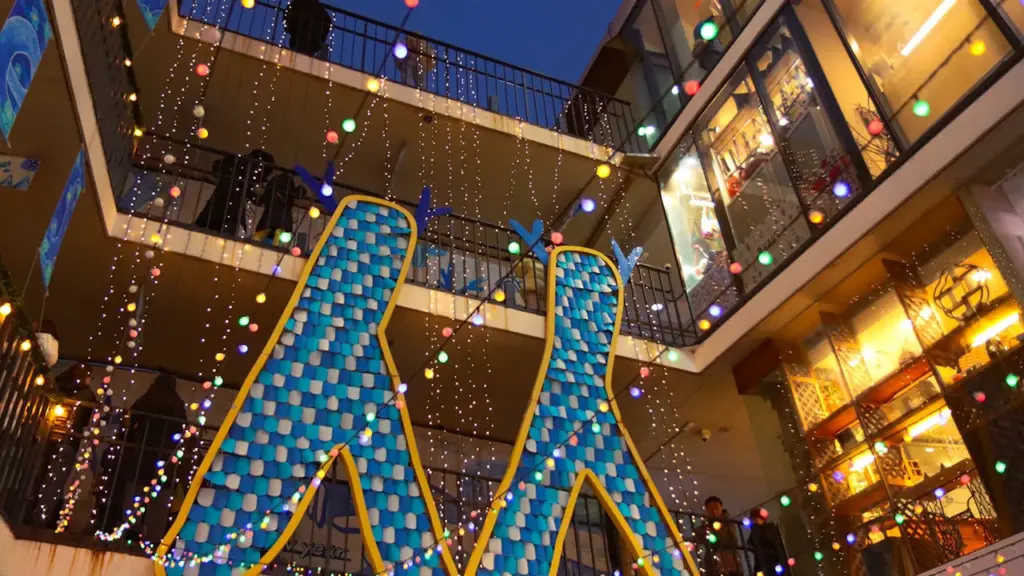Décorations lumineuses colorées dans une cour urbaine lors d'une soirée estivale festive.
