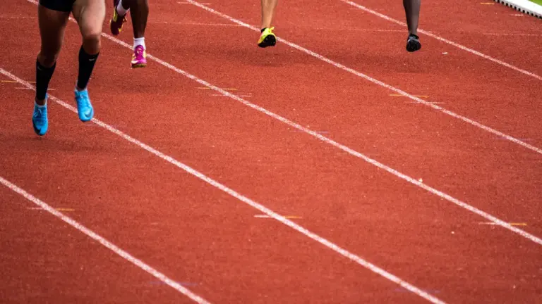 Athlètes courant sur la piste rouge du Stadium municipal d'Albi en compétition.
