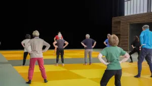 Un groupe de seniors effectue des exercices de fitness sur un tapis de gym jaune.
