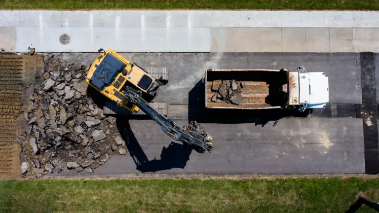 Vue aérienne de chantier routier avec pelleteuse et camion benne en pleine action.