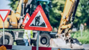 Panneau de signalisation travaux routiers avec engins de chantier en arrière-plan.