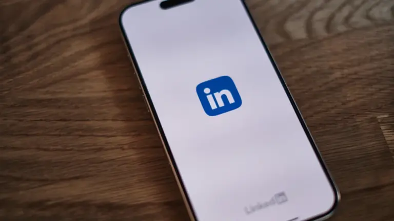 Un smartphone affichant le logo de LinkedIn sur un bureau en bois.