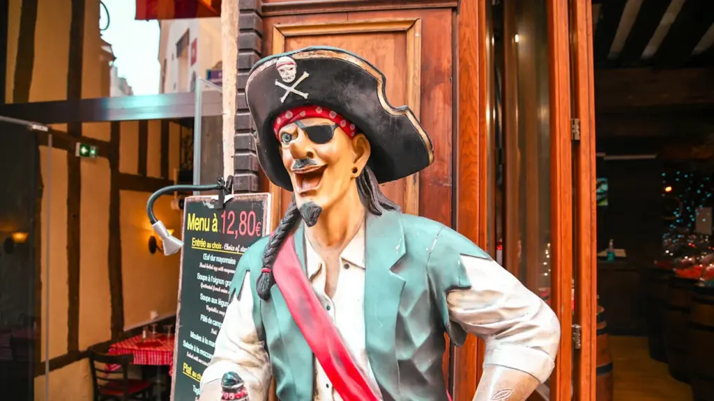 Une statue de pirate accueillante devant un restaurant avec architecture traditionnelle française.