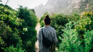 Une randonneuse marchant sur un sentier dans les collines boisées de Provence.