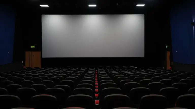 Vue d'ensemble d'une salle de cinéma vide avec grand écran et sièges sombres.