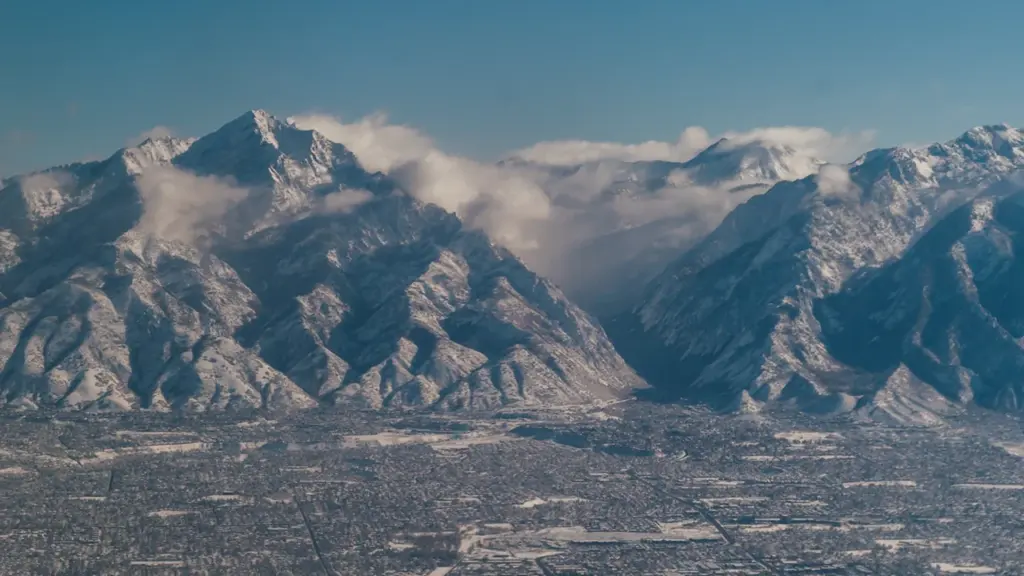 Vue aérienne panoramique sur une ville et les montagnes enneigées sous un ciel bleu.