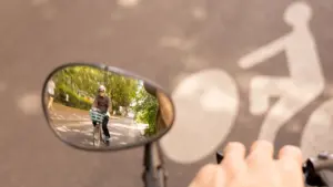 Un cycliste portant un casque est visible dans le rétroviseur d'un vélo sur piste cyclable.