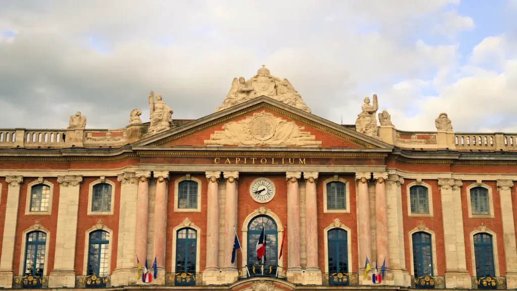 Façade majestueuse du Capitole de Toulouse sous un ciel nuageux en journée.