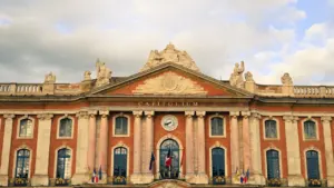 Façade majestueuse du Capitole de Toulouse sous un ciel nuageux en journée.