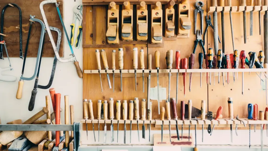 Un atelier de bricolage organisé avec divers outils manuels suspendus au mur.