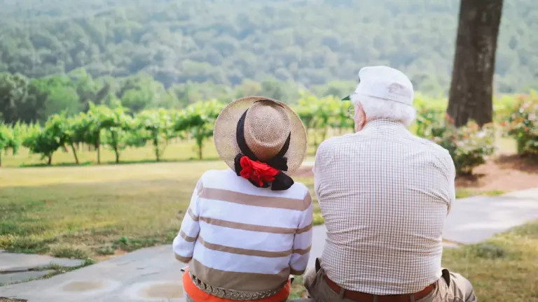 Un couple de seniors assis de dos profitant d'une vue sur la nature.