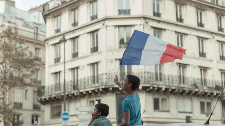 Deux jeunes garçons observent fièrement le drapeau français dans un quartier parisien.