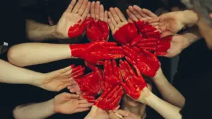 Plusieurs mains peintes en rouge forment un cœur symbolique pour le don du sang.