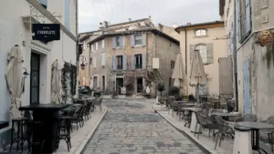 Une rue pavée avec des tables et chaises disposées en extérieur.