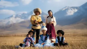 Une famille en costumes traditionnels posant dans un grand champ ensoleillé sous les montagnes.