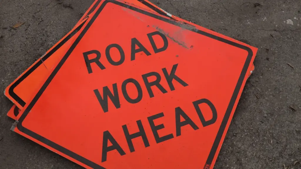 Panneau de signalisation orange indiquant des travaux routiers en cours sur la chaussée.
