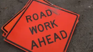 Panneau de signalisation orange indiquant des travaux routiers en cours sur la chaussée.