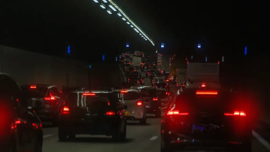 Vue nocturne de voitures circulant dans un tunnel urbain sombre et éclairé.
