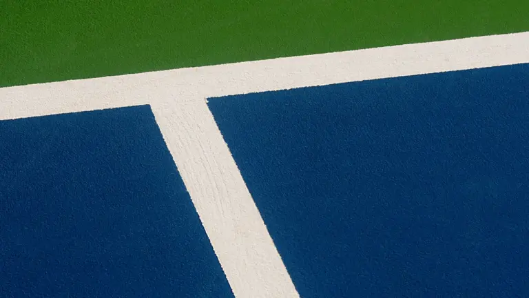 Vue rapprochée des lignes blanches sur un terrain de sport bleu et vert.