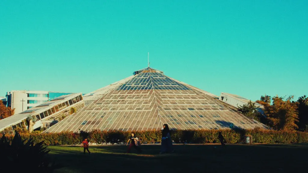 Grande structure pyramidale en verre au Jardin botanique sous un ciel clair.