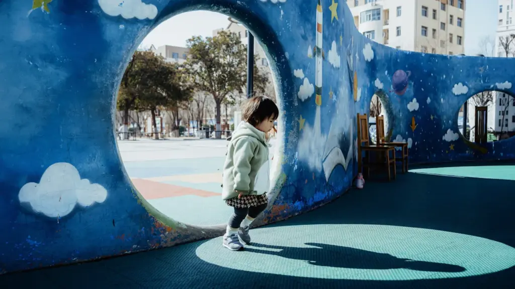 Une enfant traverse un tunnel de terrain de jeu coloré et ludique à Roubaix.