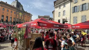 Une place de ville pavée animée avec des tentes rouges Intermarché et une foule.