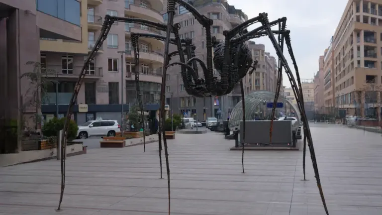 Une grande sculpture métallique d'araignée installée dans une rue piétonne de la ville.