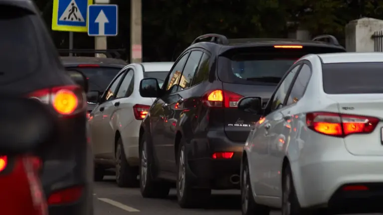Voitures à l'arrêt sur une route urbaine sous un panneau de signalisation piéton.