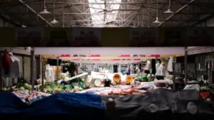 Vue intérieure d'un marché couvert avec des étals de fruits et légumes frais.