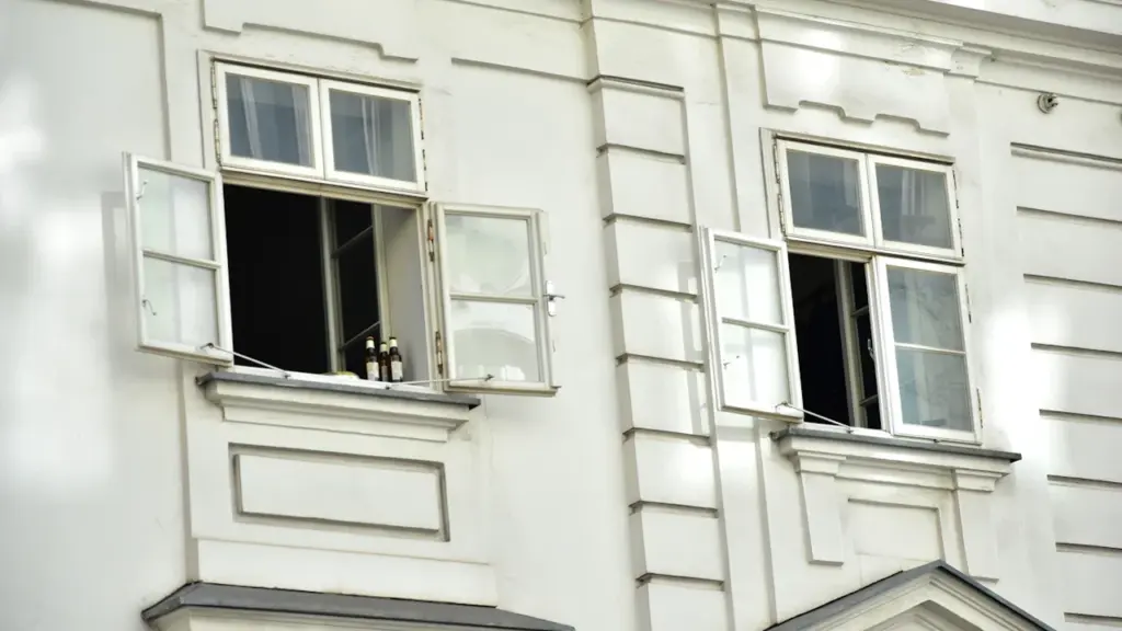 Fenêtres ouvertes sur la façade d'un bâtiment blanc lors d'une journée ensoleillée.
