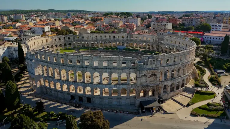 Vue aérienne impressionnante d'un ancien amphithéâtre romain préservé dans une ville moderne.