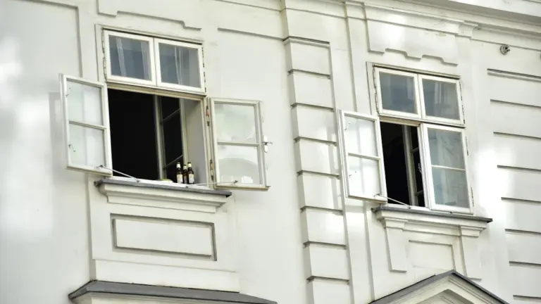Façade d'un bâtiment blanc avec des fenêtres ouvertes pour aérer pendant la canicule.