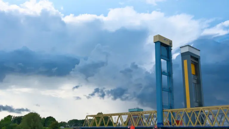 Pont levant en acier au-dessus de l'eau sous un ciel nuageux dramatique.