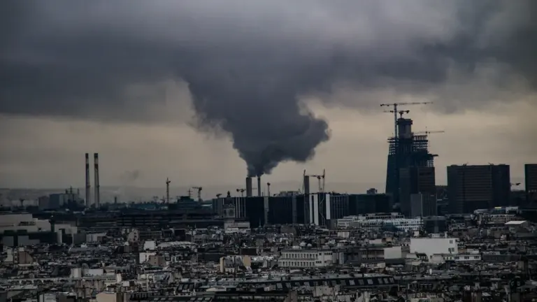 Une vue urbaine avec des cheminées industrielles rejetant de la fumée dans le ciel.