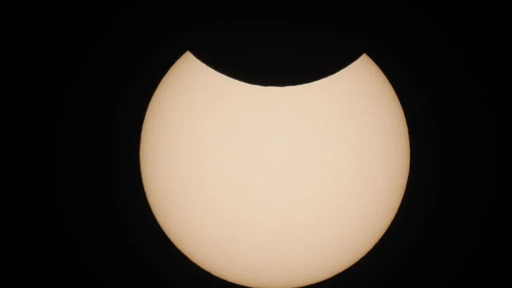 Le disque du soleil est partiellement masqué par la lune sur fond noir.