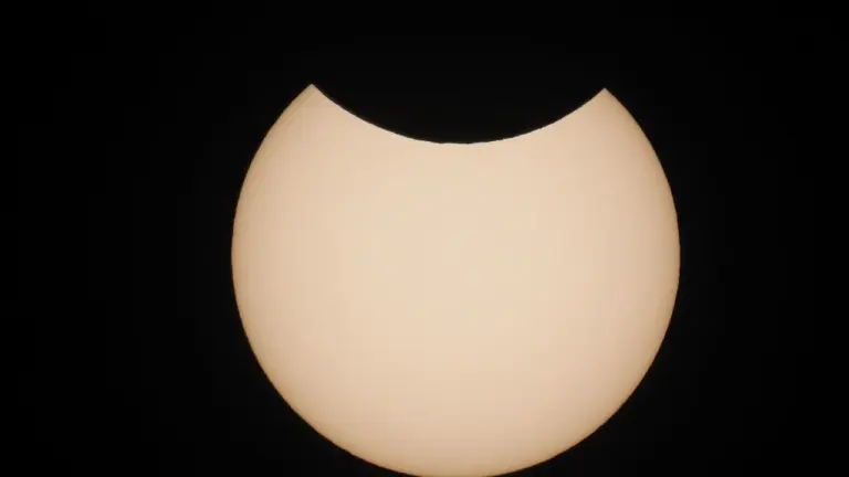 Le disque du soleil est partiellement masqué par la lune sur fond noir.