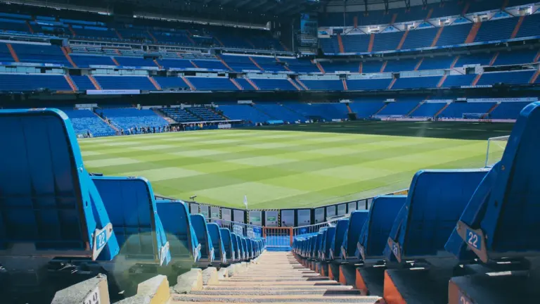 Stade de football moderne avec gradins vides sous une lumière de journée claire.