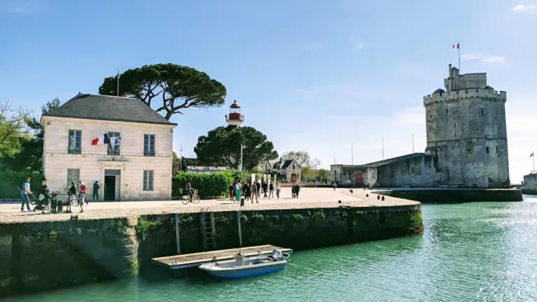 Vue panoramique du port de La Rochelle avec sa tour historique et un bateau.