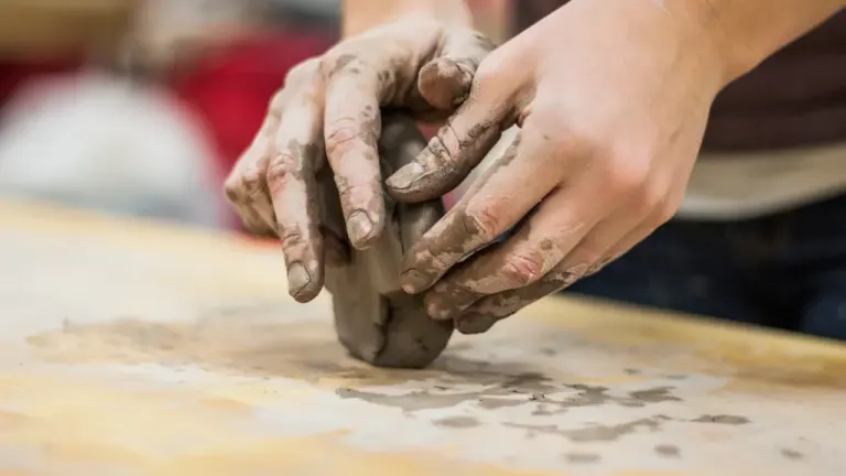 Mains d'un artisan travaillant l'argile lors d'un atelier de poterie et modelage.