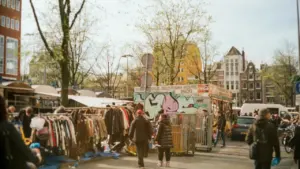 Vêtements exposés sur des portants dans une rue animée lors d'un événement commercial extérieur.